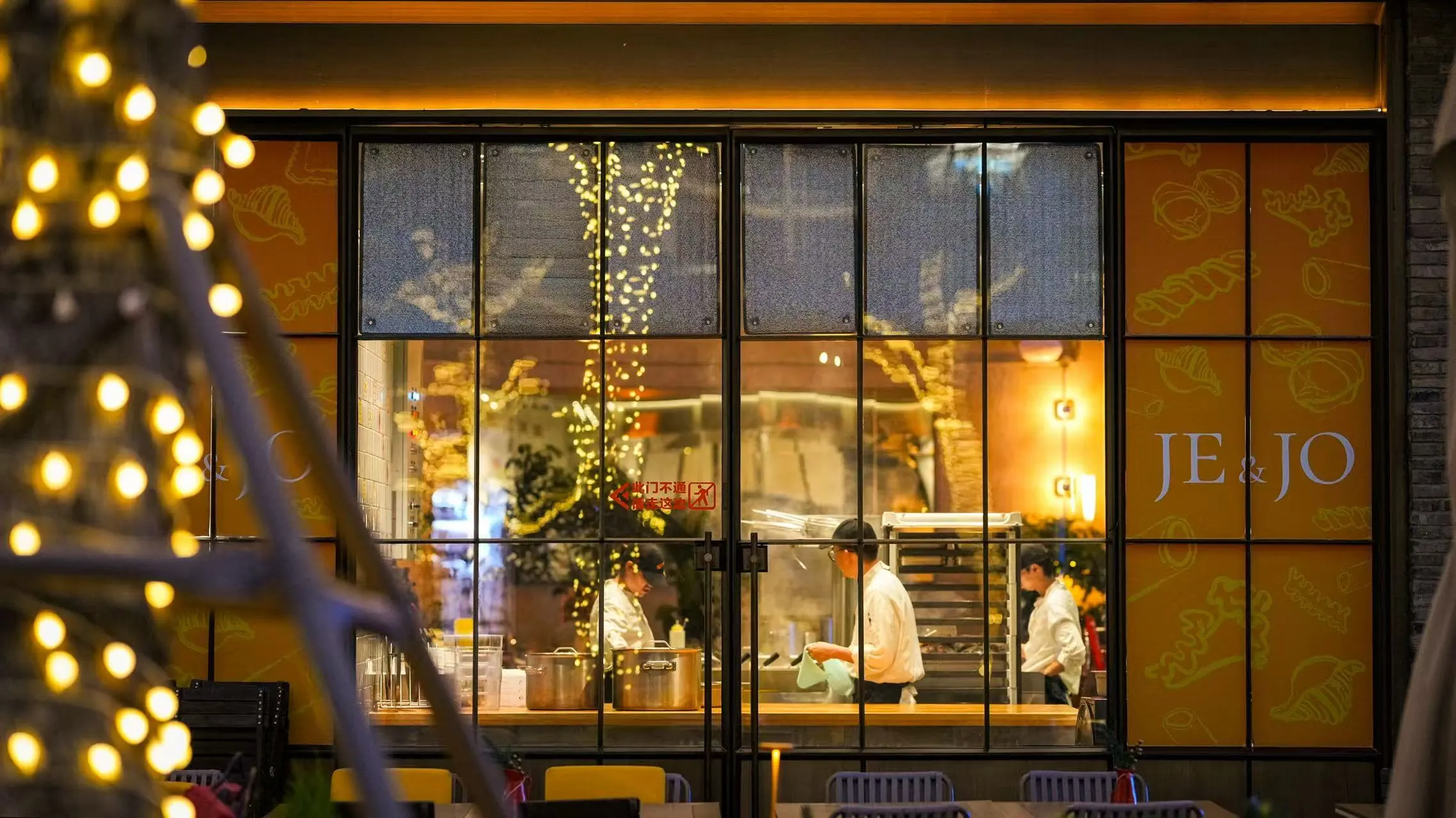 JE&JO at night, chefs at work in the open kitchen seen through the glass